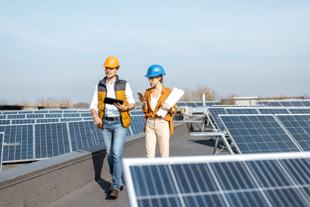 Two engineers examining the construction of a solar power plant, walking with digital tablet.